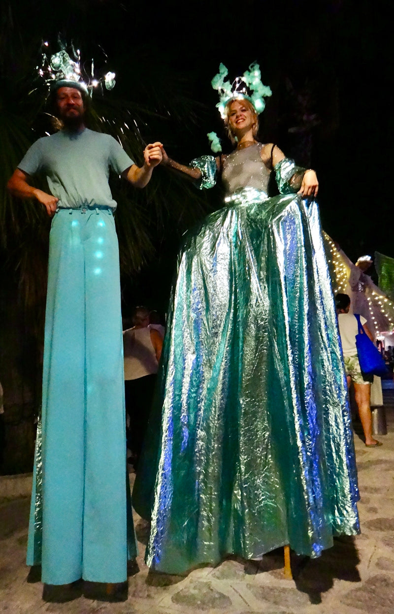 Two stilt walkers in illuminated costumes at night